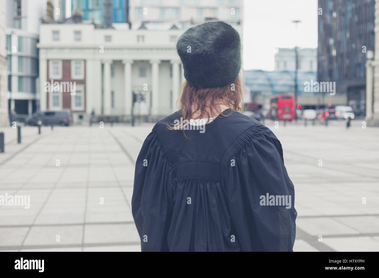 Eine junge Frau trägt eine Pelzmütze und ein schwarzer Graduierung Kleid steht in einem Quadrat Stockfoto