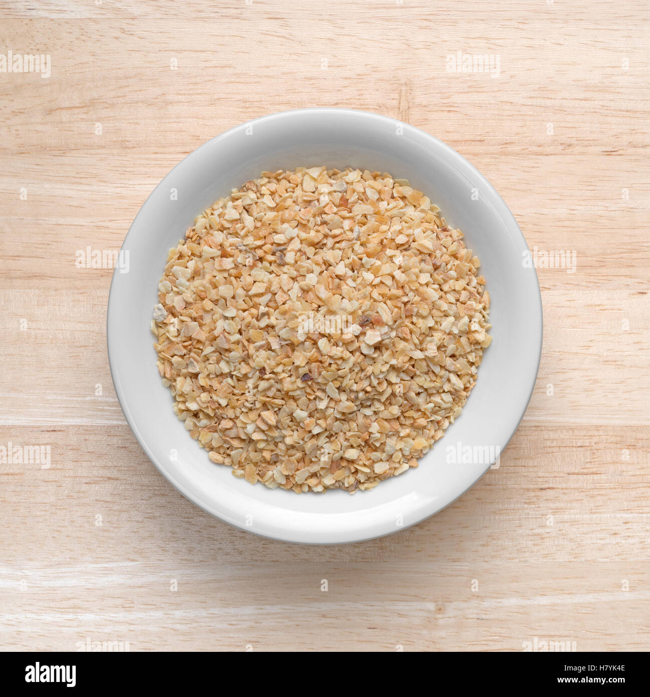 Draufsicht auf eine kleine Schüssel gefüllt mit getrockneten Knoblauch auf einem Holztisch. Stockfoto