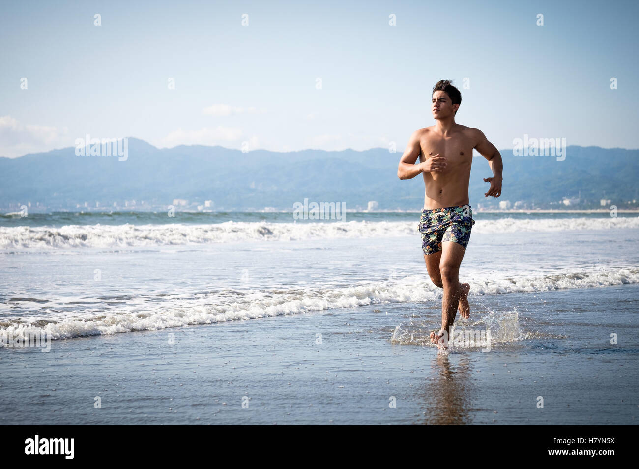 Junger Mann in Badeshorts ist am Strand joggen. Riviera Nayarit, Nuevo Vallarta, Mexiko Stockfoto