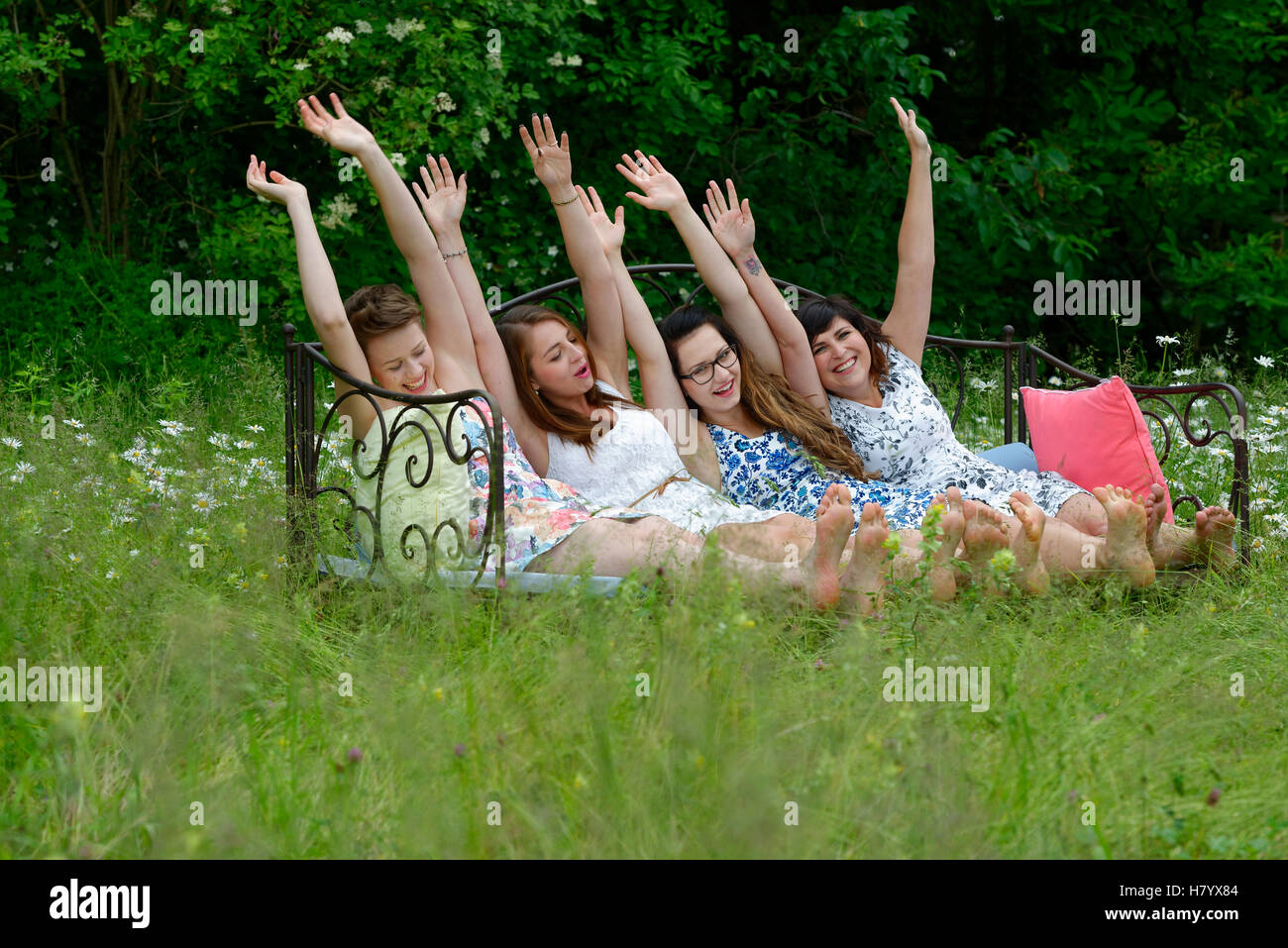 Junge Frauen sitzen auf Sofa, posieren, verspielt, Wiese, Upper Bavaria, Bavaria, Germany Stockfoto