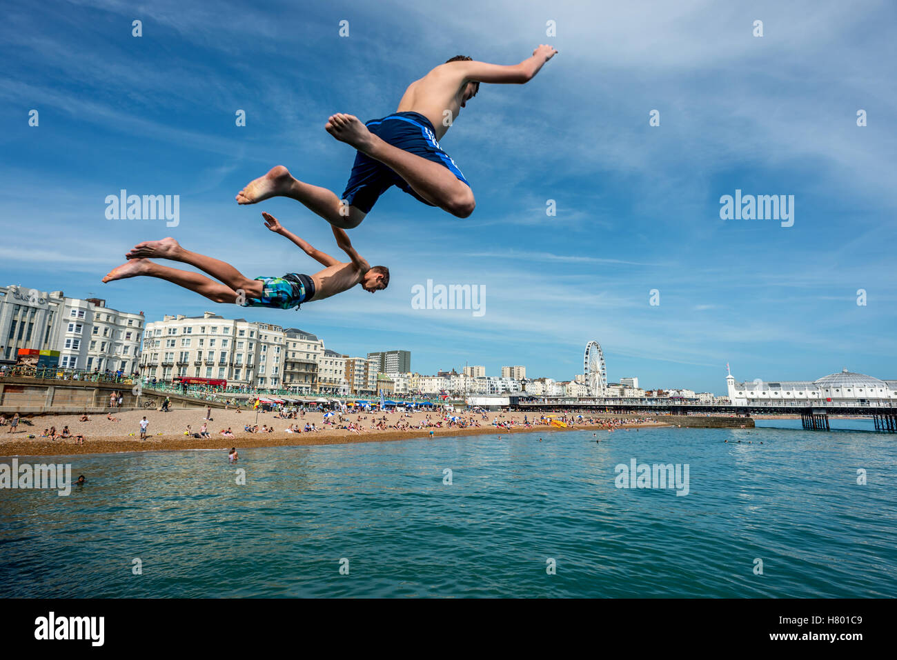 Jungs springen aus Brighton Seafront ins Meer. Stockfoto