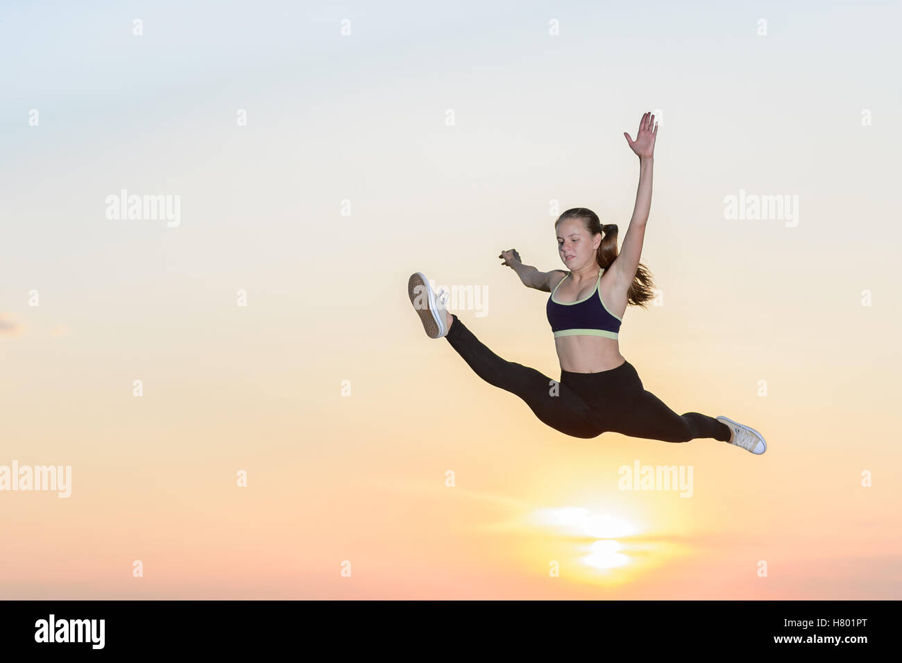 Das junge Mädchen engagiert im Kunstturnen bei Sonnenuntergang Hintergrund Stockfoto