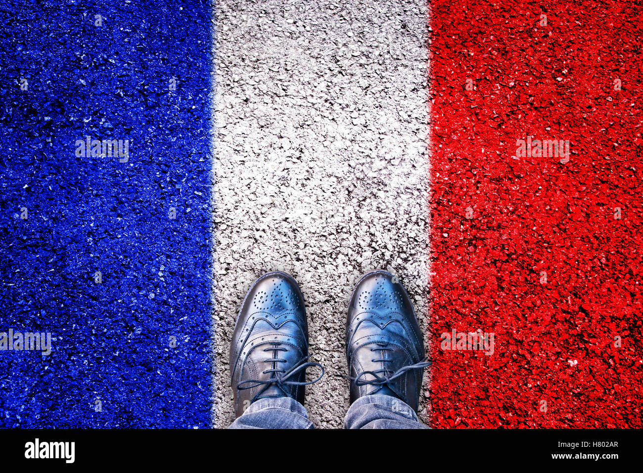 Beine und Schuhe auf Asphalt mit französischer Flagge Stockfoto