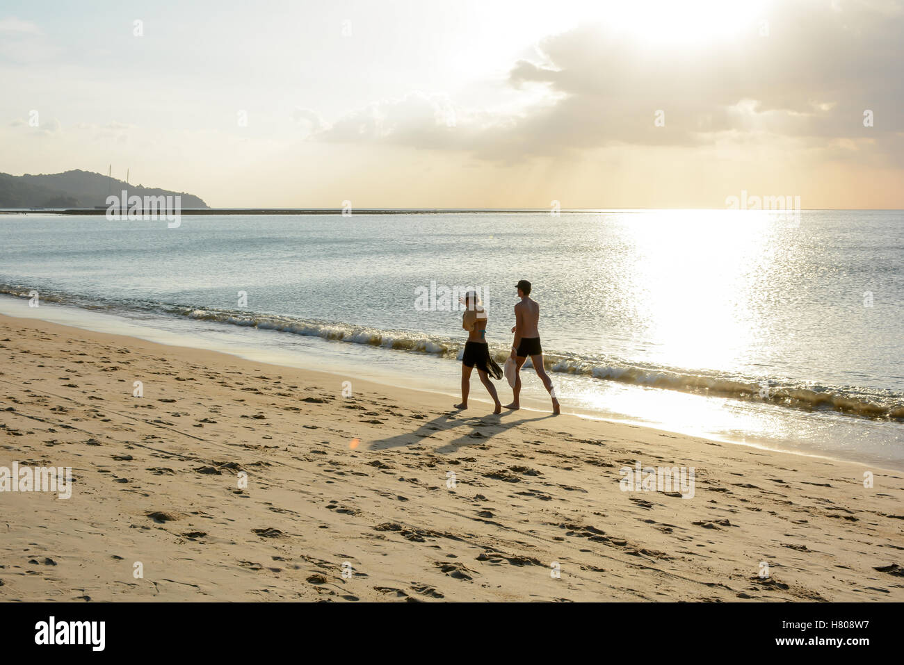 Älteres Paar zu Fuß am Strand und goldene schöne Himmelslicht reflektierenden am Ozean. Stockfoto