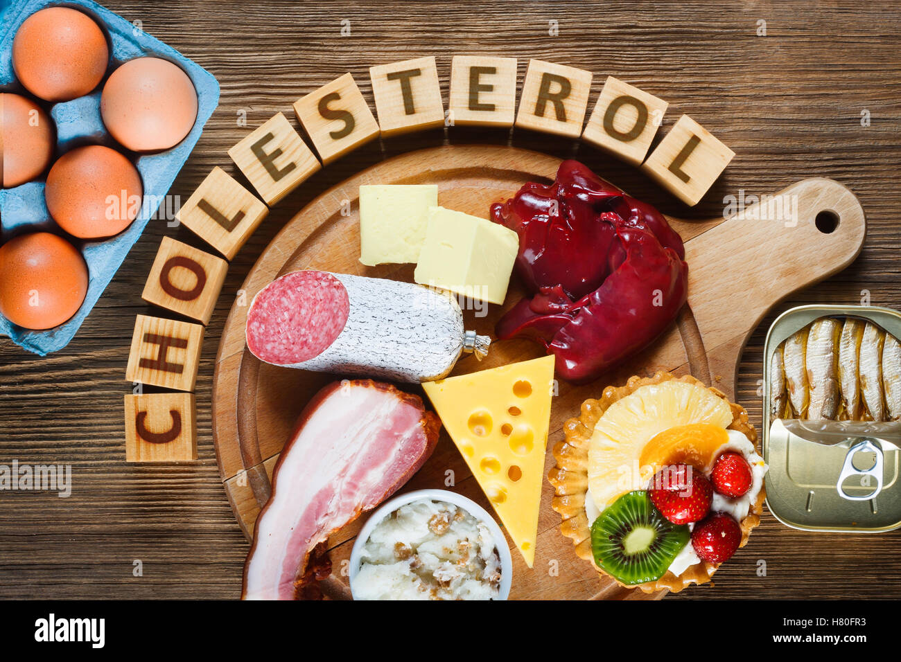 Lebensmittel reich an Cholesterin wie Eiern, Leber, gelben Käse, Butter, Speck, Schmalz mit Zwiebeln, Sardinen in Öl und süßes Dessert - cup Stockfoto