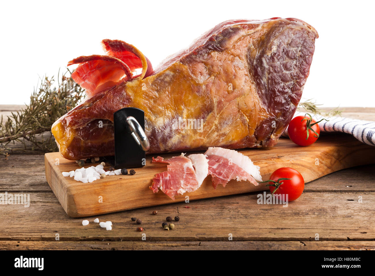 Stillleben mit trocken-kuriert Serranoschinken mit Schinken Halter, Salz, Pfeffer, Tomaten auf rustikalen Tisch, weißer Hintergrund Stockfoto