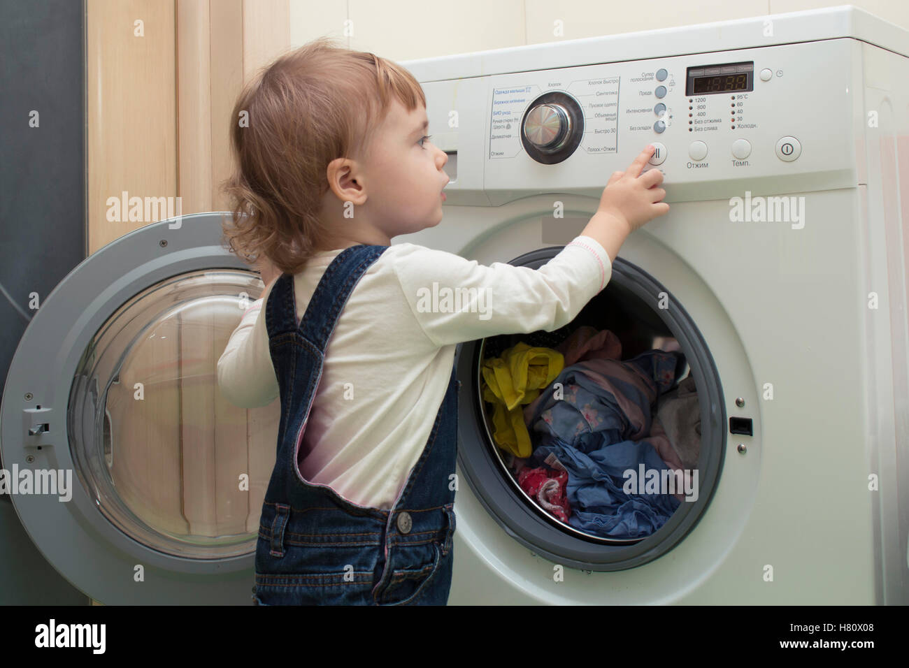 Das kleine Kind beginnt Waschmaschine. Mutters Helfer. 2 Jahre alt  Stockfotografie - Alamy