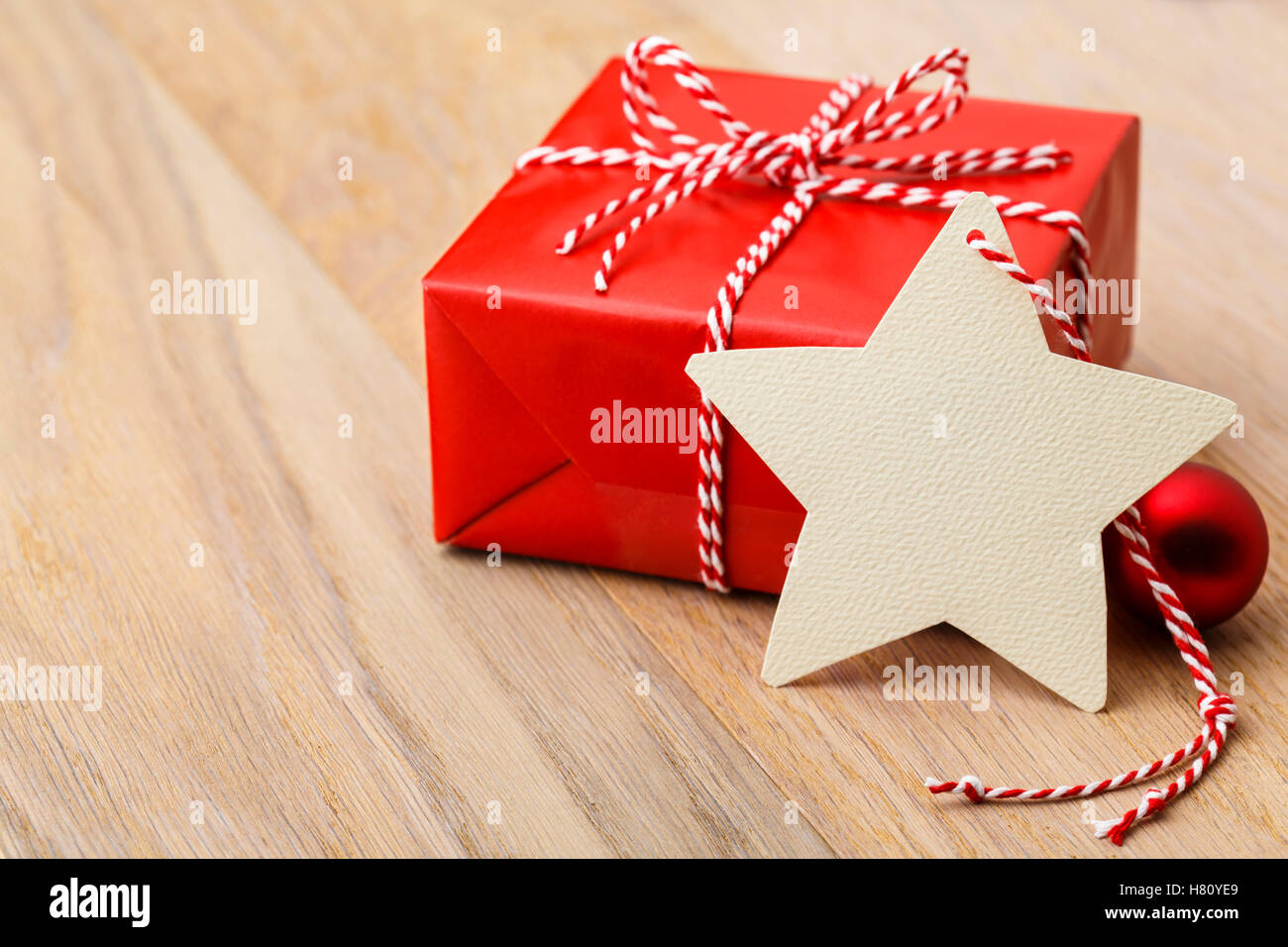 Einfache, klassische rote Weihnachtsgeschenk mit handgefertigten leer Geschenkanhänger auf rustikalen Holz horizontale Hintergrund präsent. Stockfoto