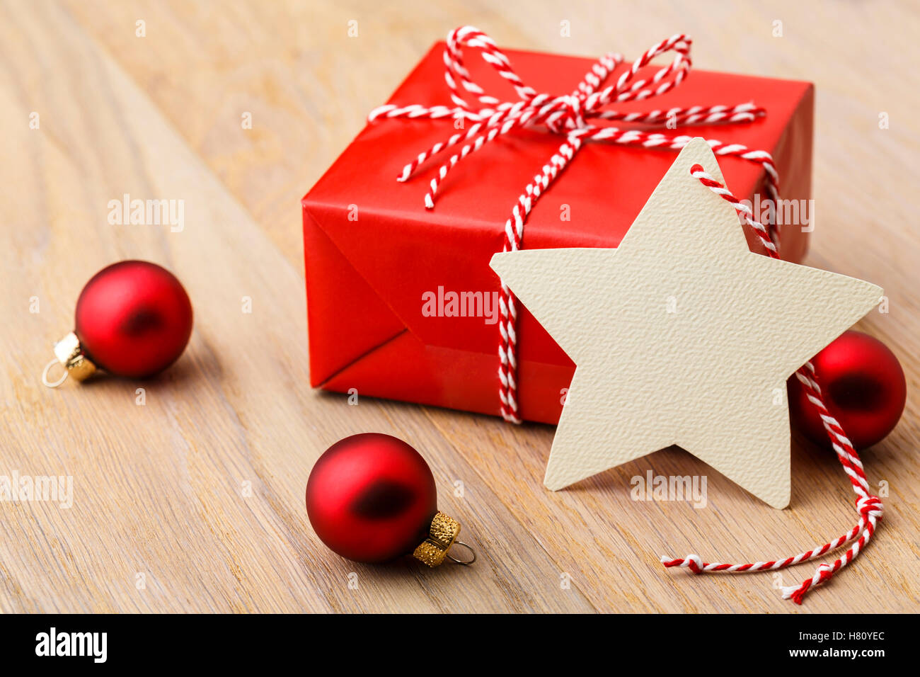 Einfache, klassische rote Weihnachtsgeschenk mit Ornamenten und handgemachte leer Geschenkanhänger auf rustikalen Holz horizontale Hintergrund vertreten. Stockfoto