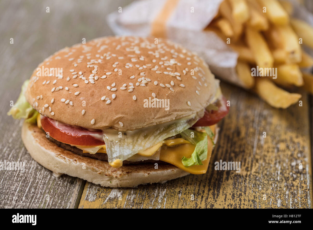 Hamburger und Pommes Frites auf einem alten Schreibtisch aus Holz Stockfoto