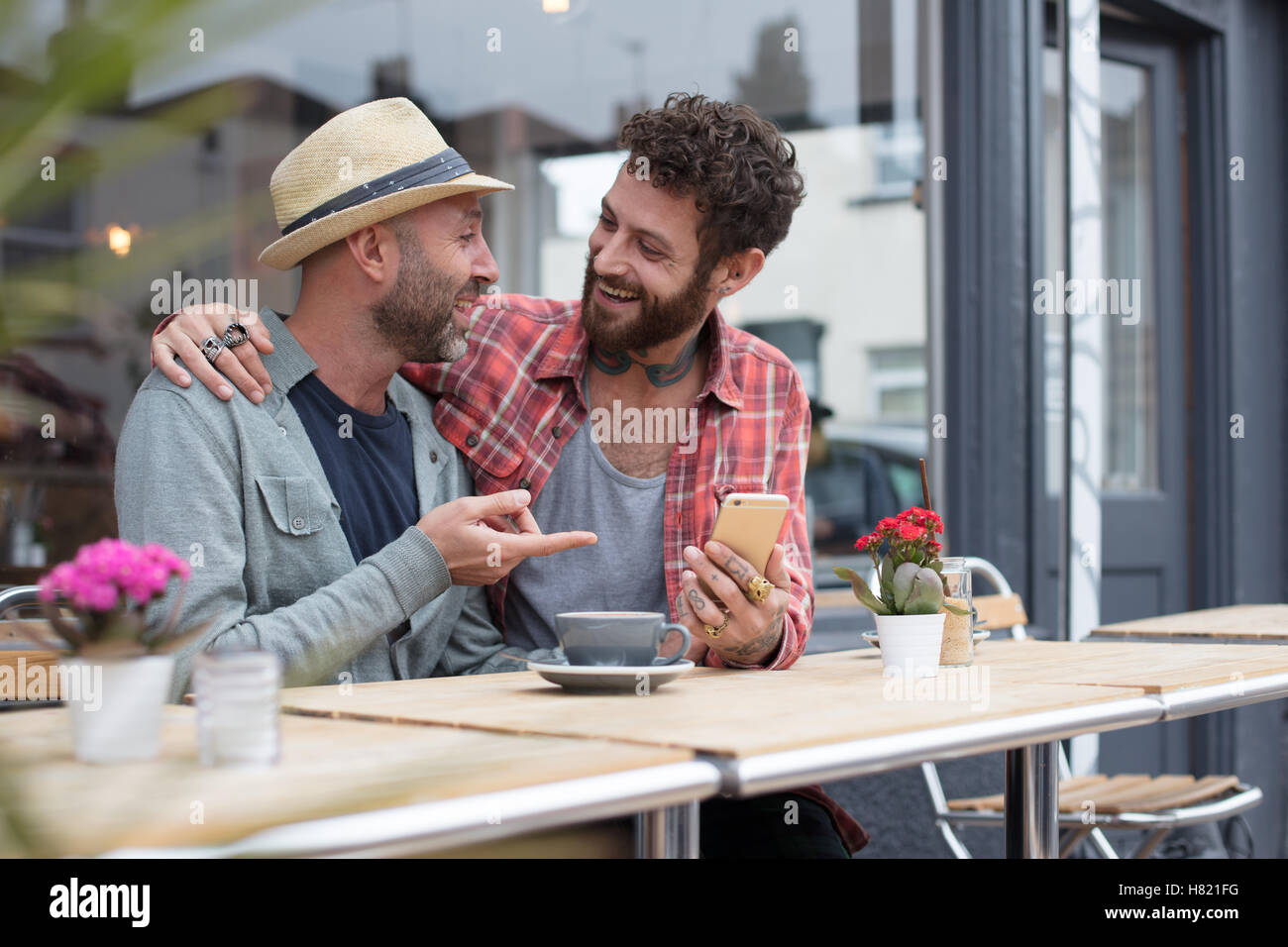 Gay paar saß sharing Telefon im café Stockfoto