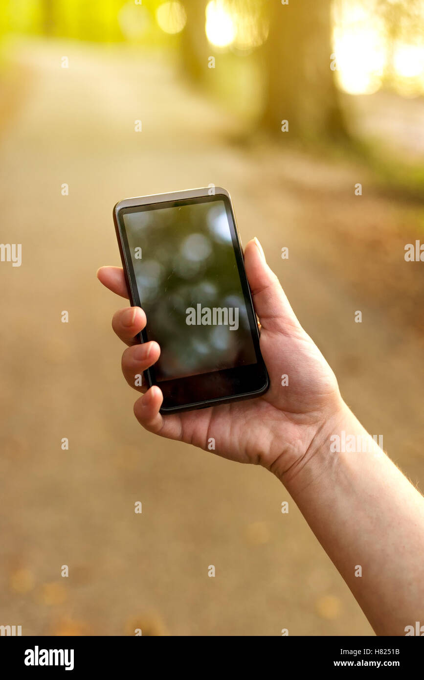 Auf der Suche nach GSM-Signal in den Wald, weibliche Hand halten Handys hoch und versucht, Netzwerk finden Stockfoto