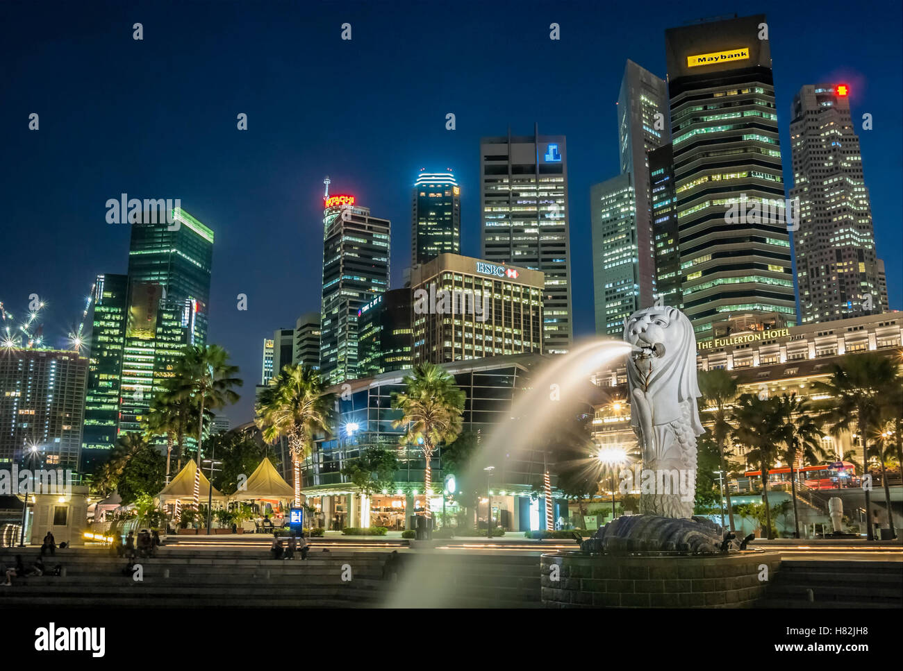 Nacht-Bild von der hell erleuchteten Merlion neben der Skyline und Fullerton Hotel in Marina Bay, Singapur Stockfoto