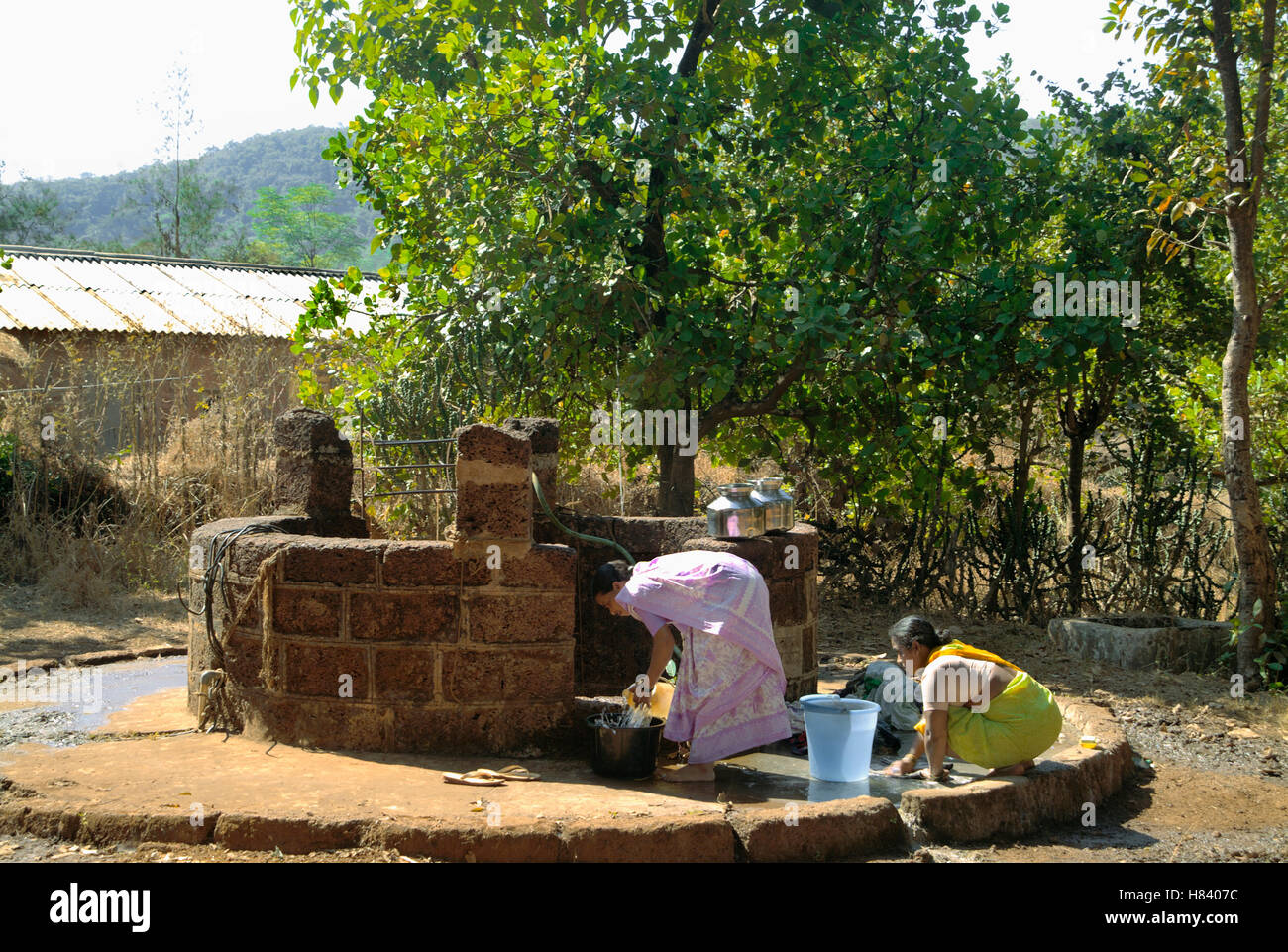 Dorfbewohner, die Hausarbeit in der Nähe des Brunnens zu tun. Stockfoto