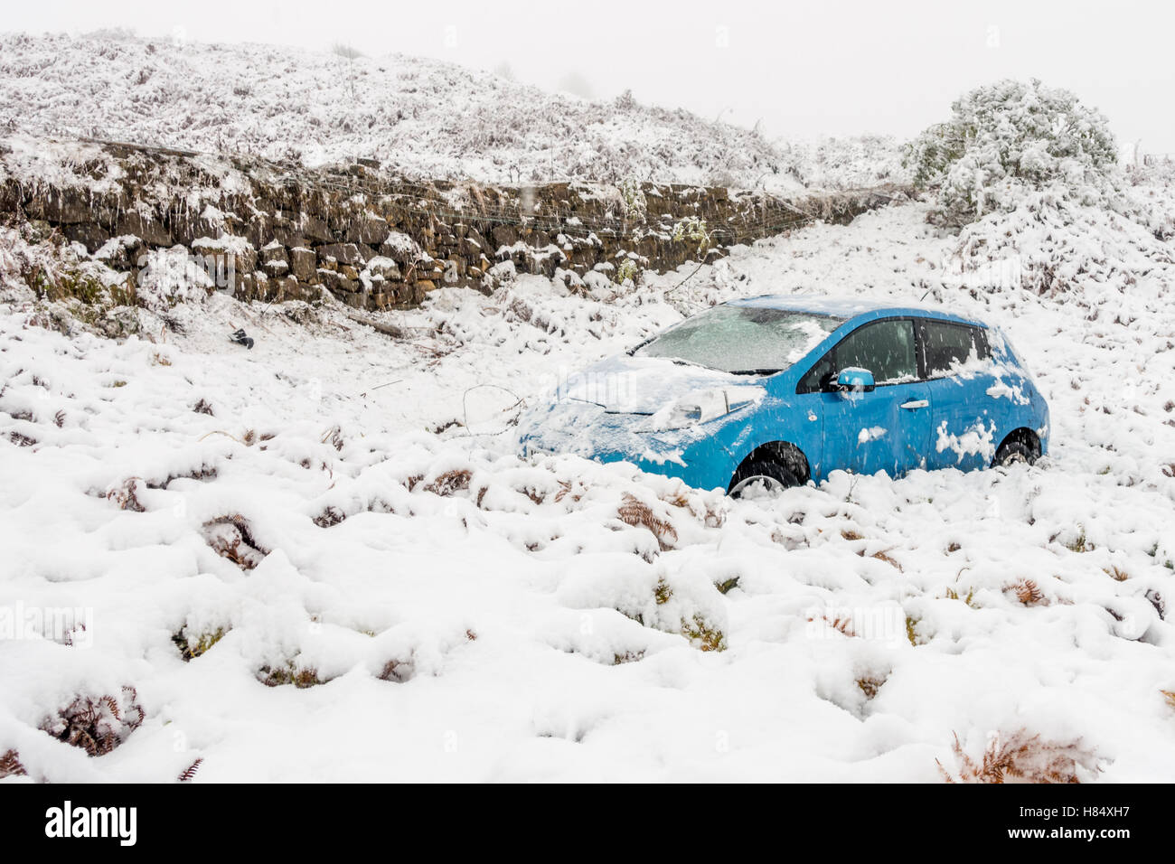 Leeds, West Yorkshire, Großbritannien. 9. November 2016. Auto rollt der Straße oberhalb in den schneebedeckten Bedingungen frühmorgens am Kuh & Kalb Moor Road, Ilkley, UK. Fußspuren zeigen, dass Fahrer ging. Bildnachweis: Rebecca Cole/Alamy Live-Nachrichten Stockfoto