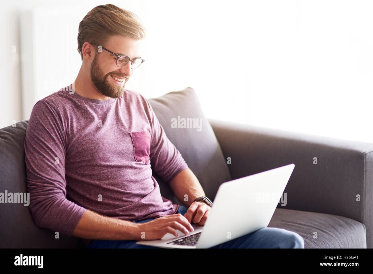 Gut aussehender Mann mit Laptop zu Hause Stockfoto