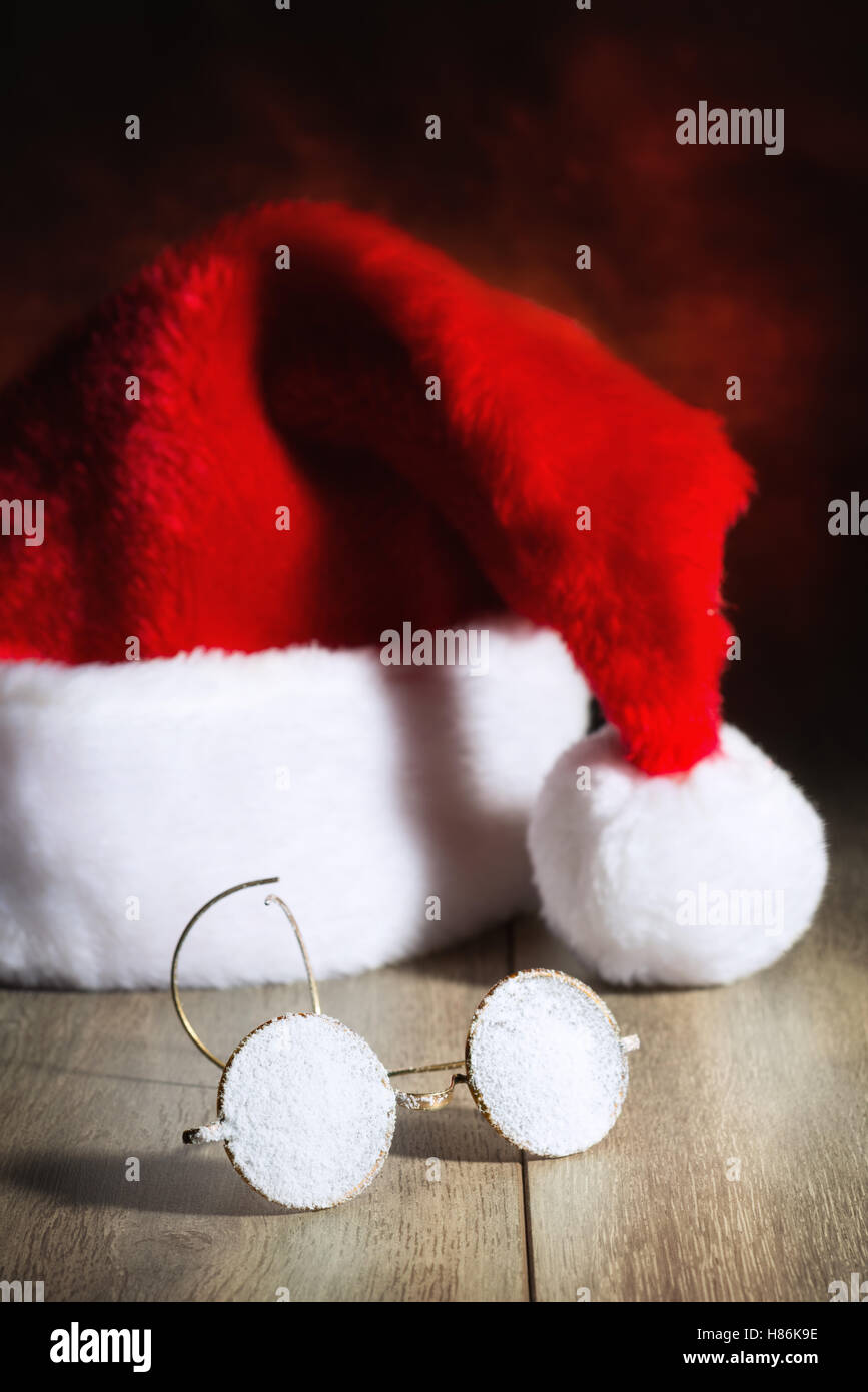 Santas Gläser mit Schnee bedeckt mit Hut im Hintergrund Stockfoto