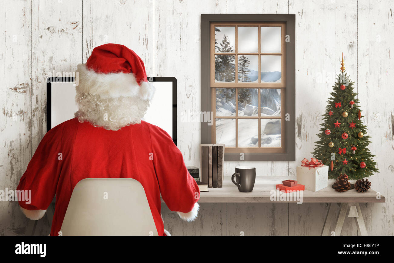 Kalte Winterzeit bei Santa Claus nach Hause. Weihnachtsmann online auf seinem Computer arbeiten. Weihnachtsbaum, Geschenke und Dekorationen auf Tisch. S Stockfoto