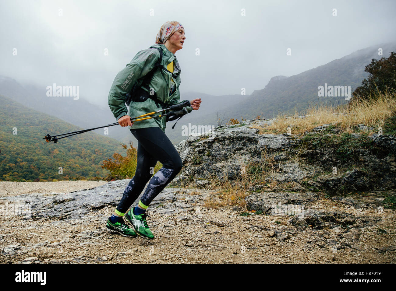 Frau mittleren Alters Läufer laufen im Regen auf einem Bergweg mit walking-Stöcken während Crimea Bergmarathon Stockfoto
