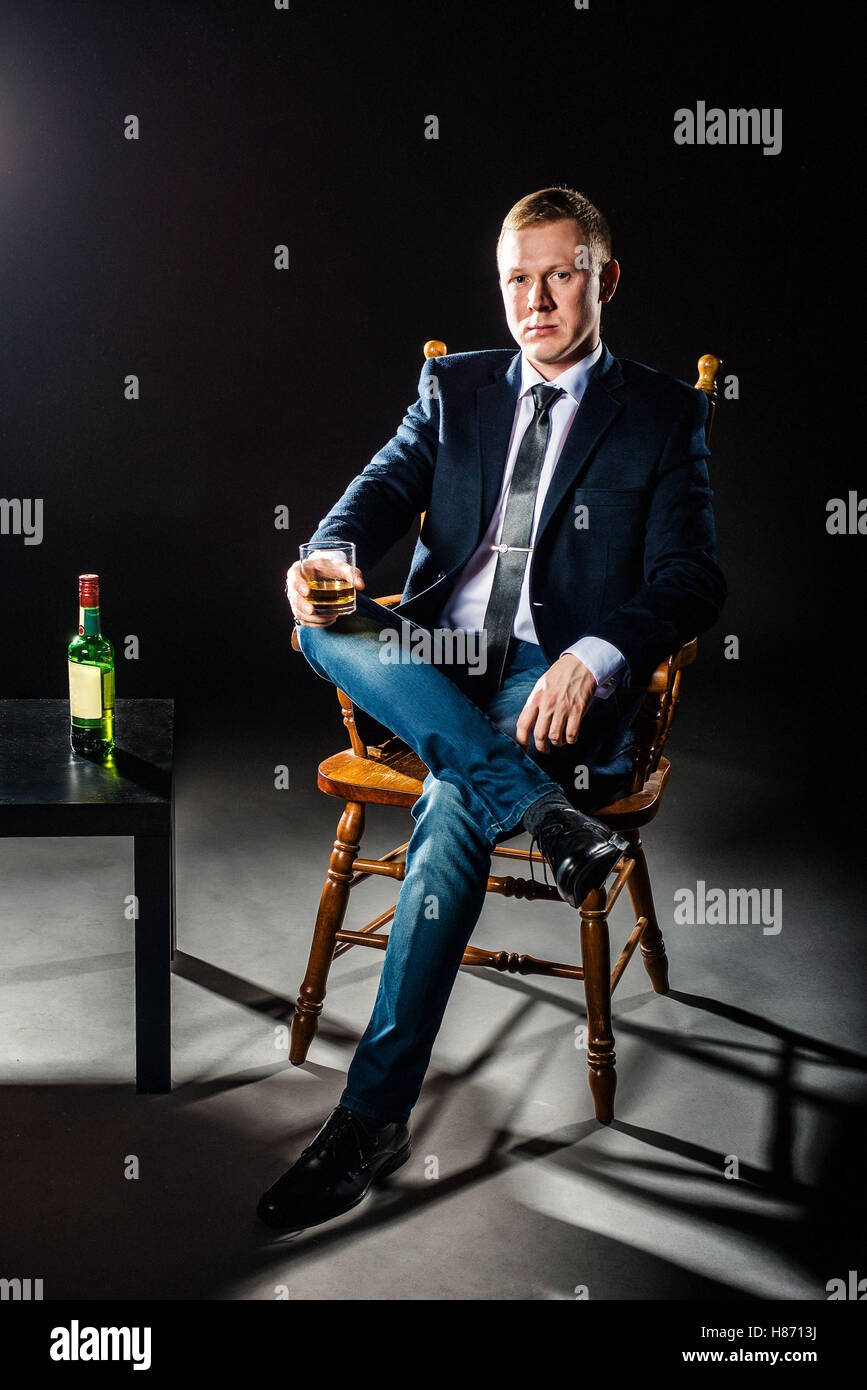 Der glückliche Geschäftsmann Glas Whisky und Blicke in die Kamera hält. Studio gedreht. Stockfoto