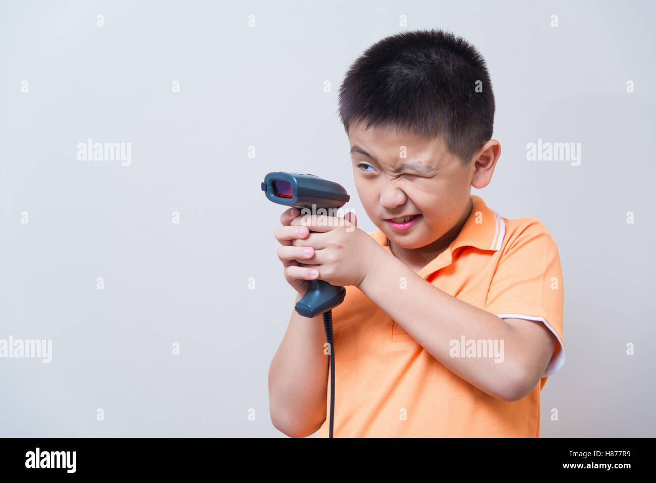 Asiatische junge Ziel ist eine gefälschte Pistole mit Barcode-Scanner,  Studio gedreht, auf graue Wand Hintergrund mit weichen Schatten gemacht  Stockfotografie - Alamy