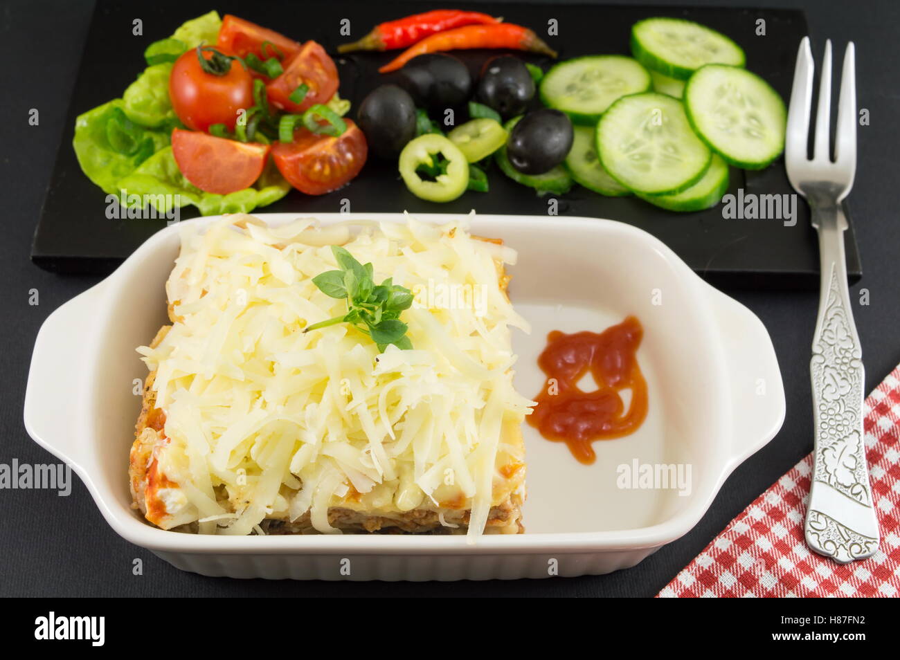 Lasagne-Teil mit frischem Gemüse auf einem Teller Stockfoto