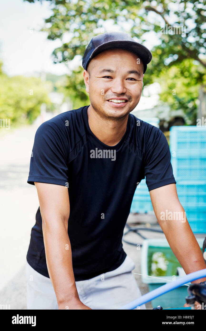 Ein junger Mann, die Arbeit auf dem Bauernhof tragen Kisten geernteten Gemüse. Stockfoto