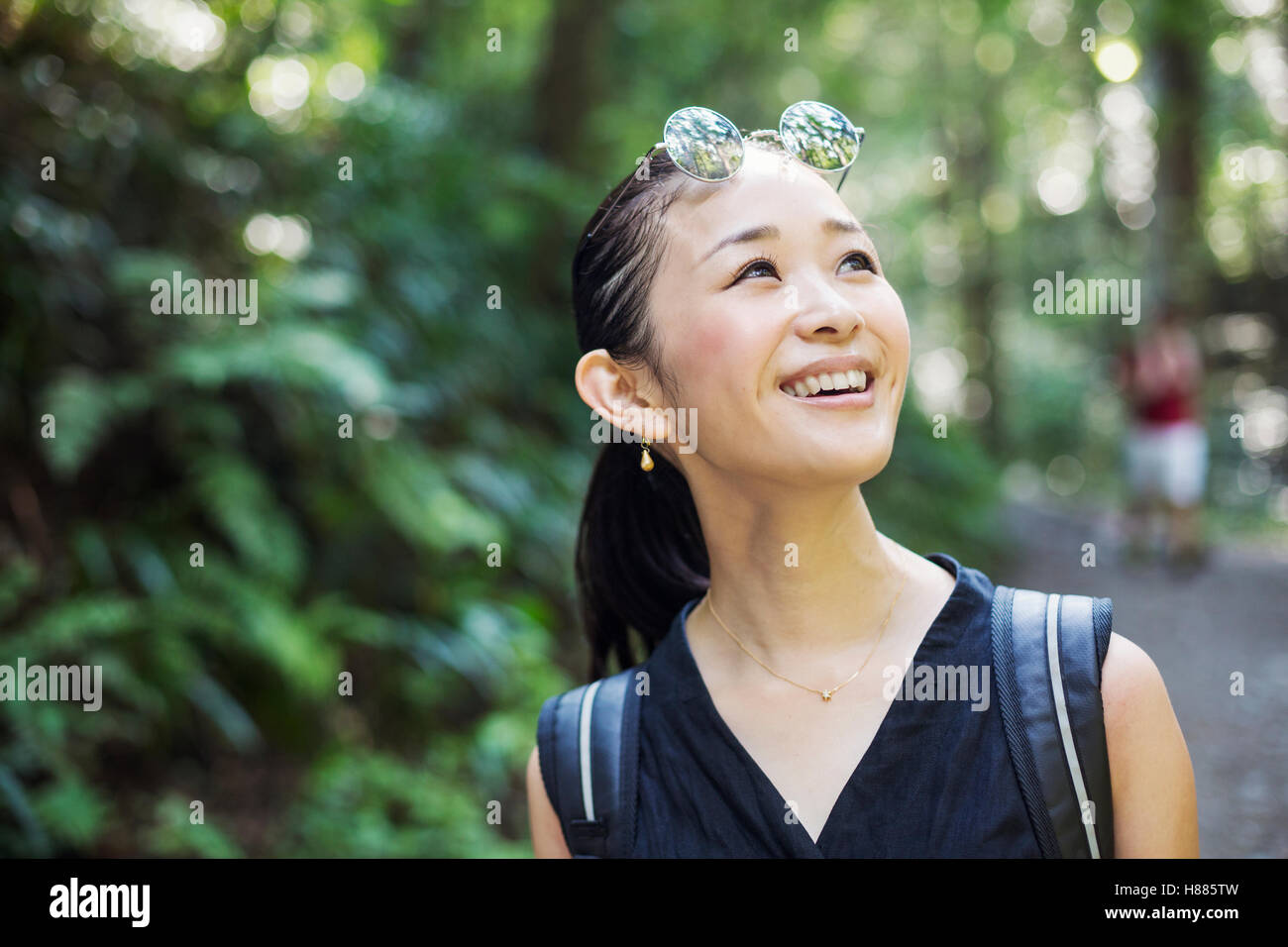 Porträt einer lächelnden jungen Frau stehend in einem Wald. Stockfoto