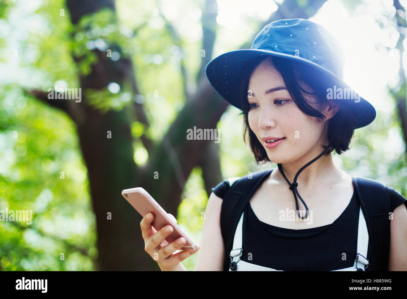 Junge Frau in einem Wald stehen, mit Hilfe eines Mobiltelefons. Stockfoto