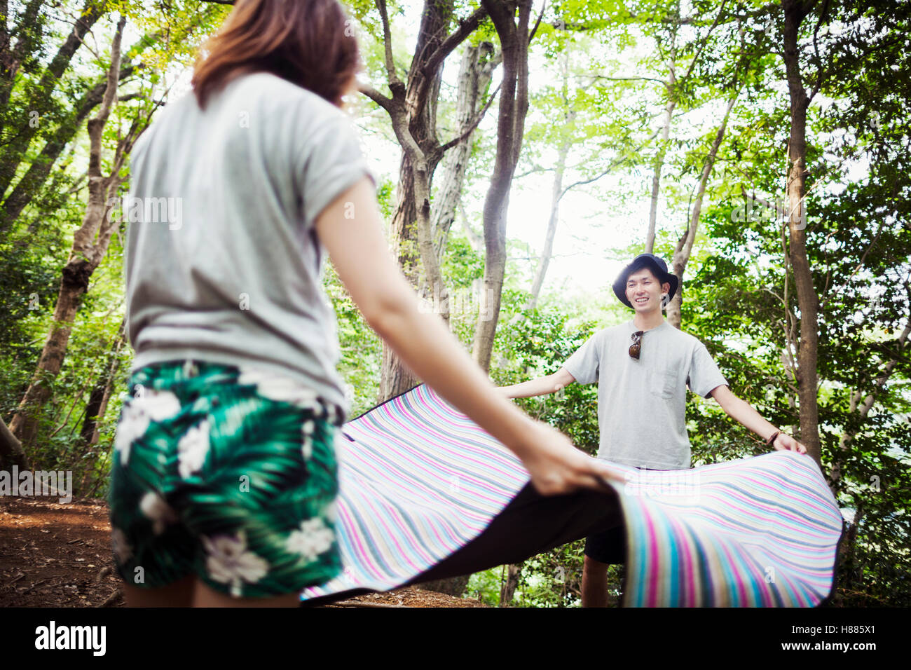Junge Frau und Mann in einem Wald steht, hält eine Picknickdecke. Stockfoto