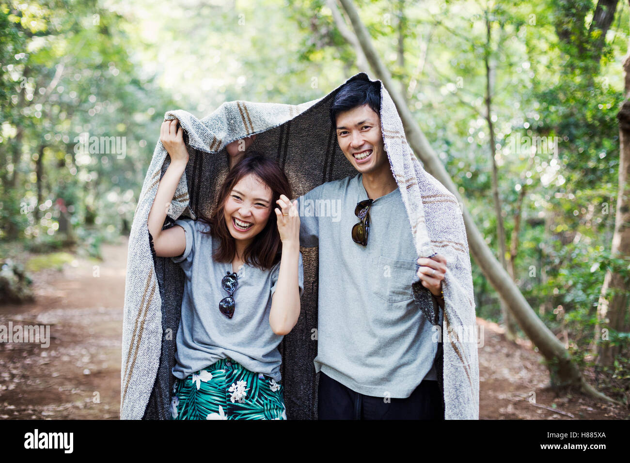 Junge Frau und Mann in einem Wald stehen, halten eine Decke über den Kopf. Stockfoto