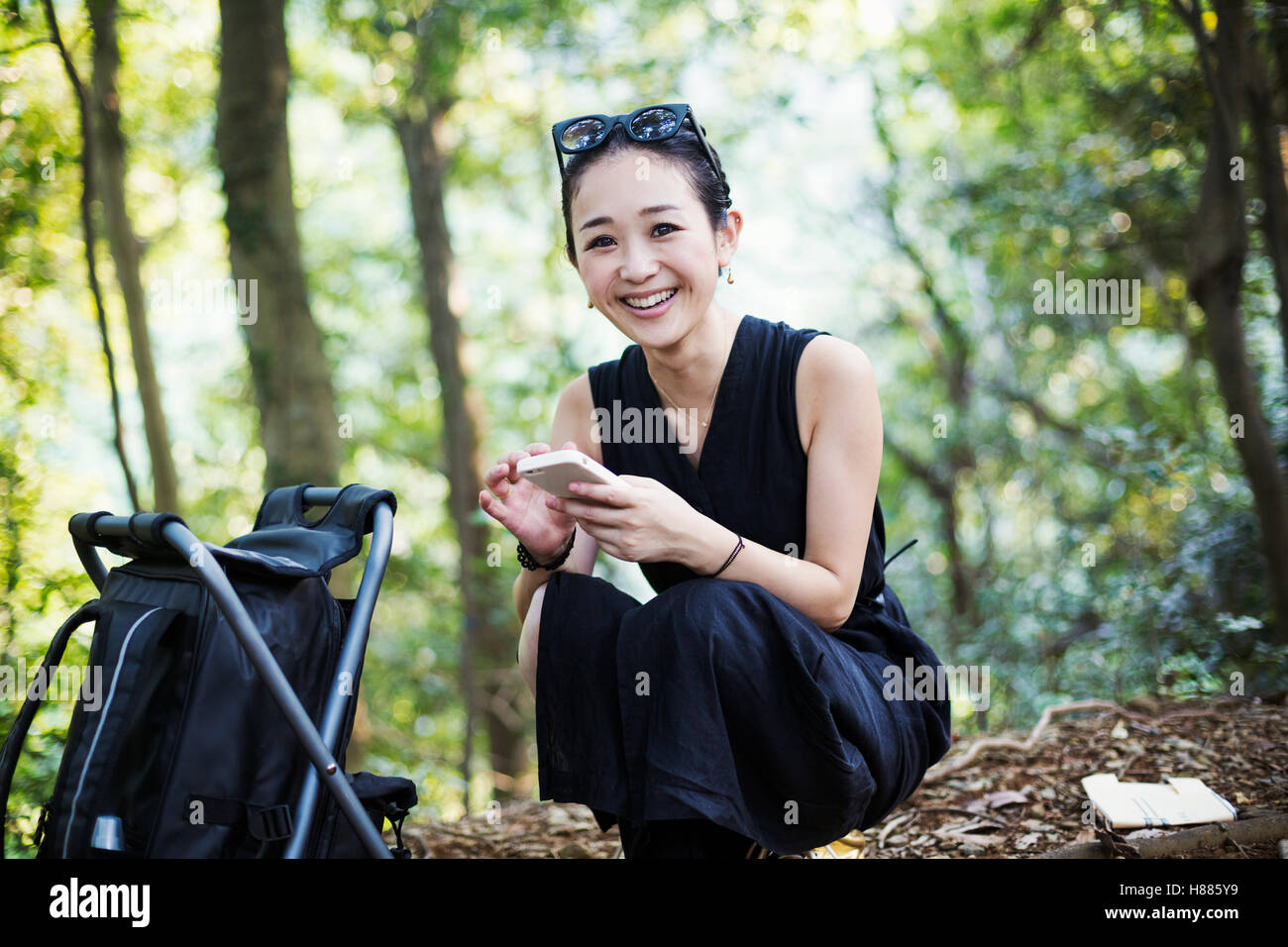 Lächelnde junge Frau sitzt in einem Wald. Stockfoto