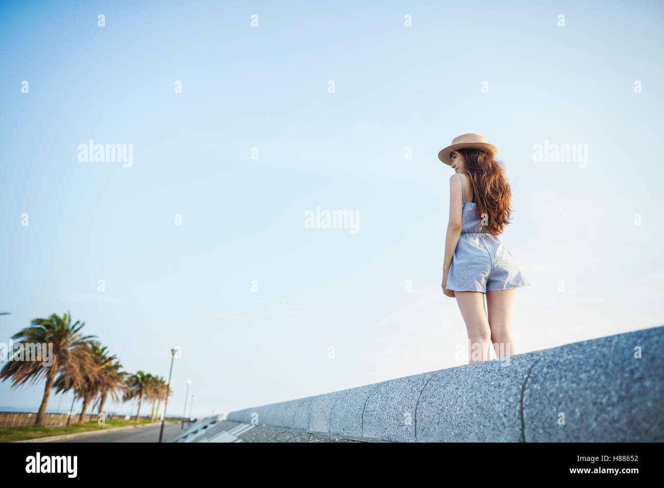 Eine junge Frau in Sommerkleidung stehend durch eine Straße, Blick in die Ferne. Stockfoto