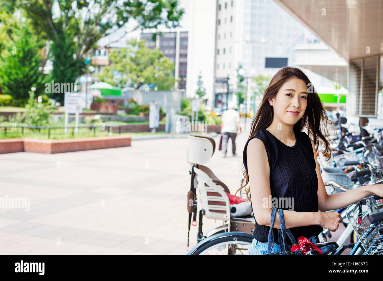 Lächelnde junge Frau mit langen braunen Haaren stand neben dem Fahrrad. Stockfoto