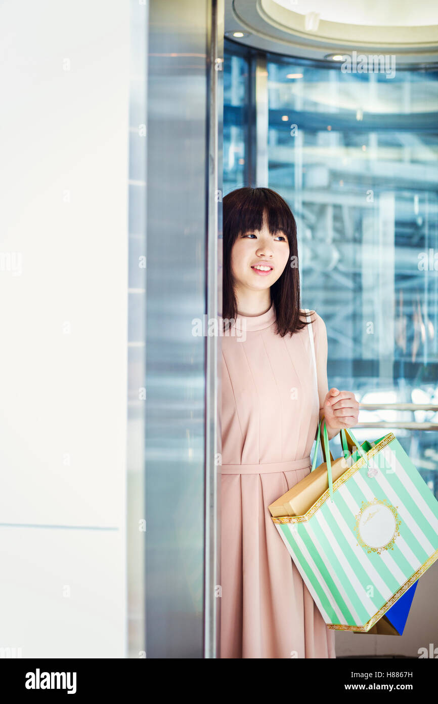 Junge Frau mit langen braunen Haaren in einem Einkaufszentrum, Einkaufstaschen tragen. Stockfoto