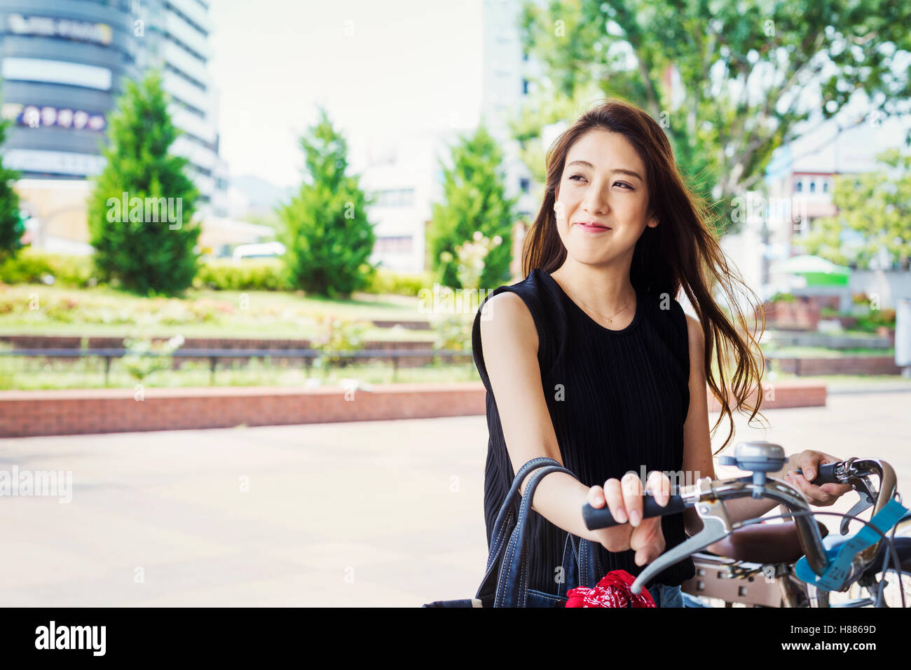 Lächelnde junge Frau mit langen braunen Haaren stand neben dem Fahrrad. Stockfoto