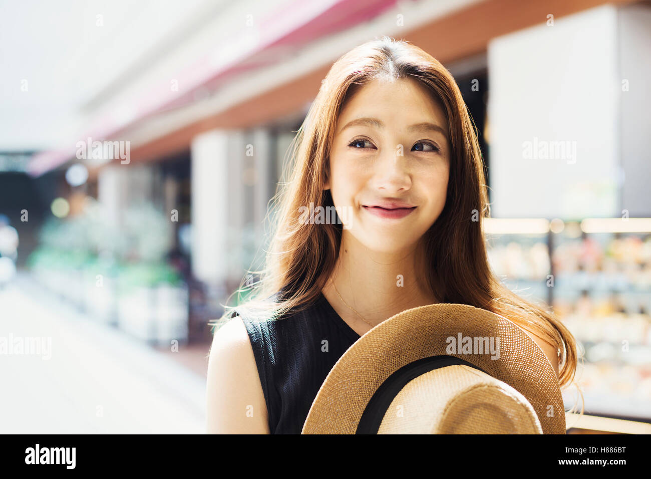 Lächelnde junge Frau mit langen braunen Haaren, mit Panamahut. Stockfoto