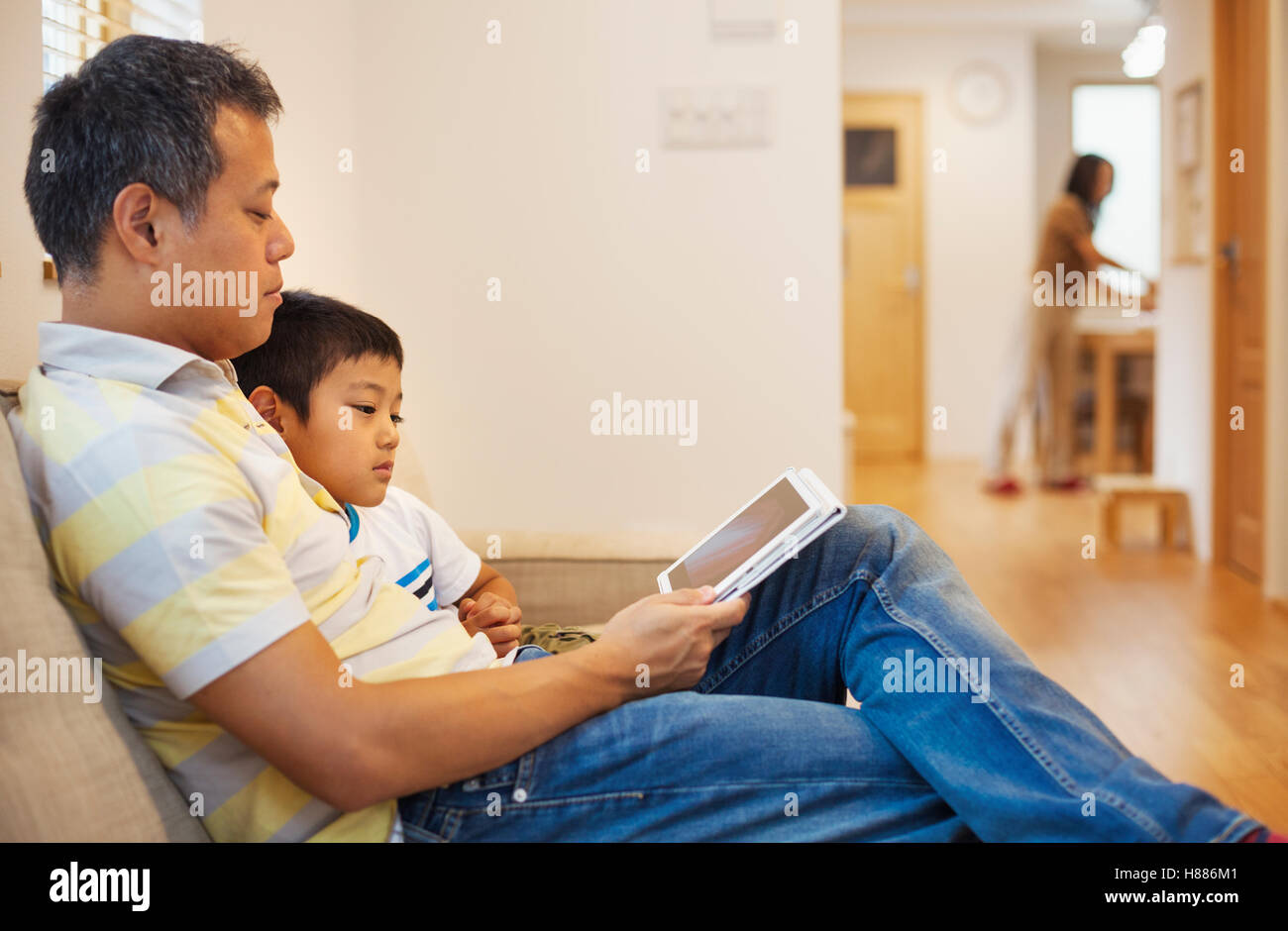 Haus der Familie. Ein Mann und sein Sohn sitzen ein Buch zu lesen. Stockfoto