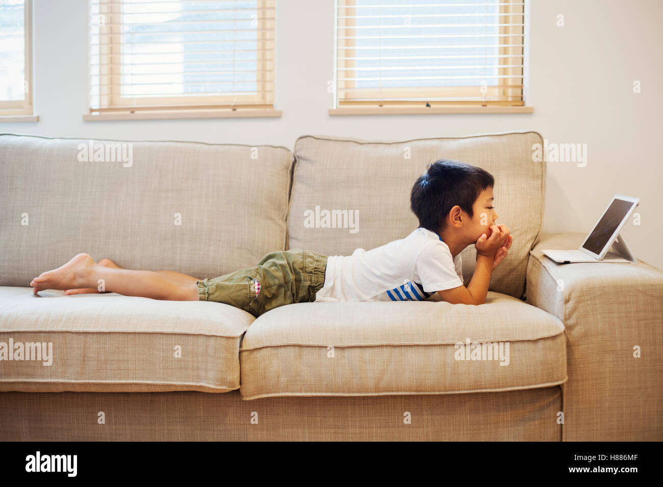 Haus der Familie. Ein Junge auf einem Sofa beobachten eine digitale-Tablette. Stockfoto
