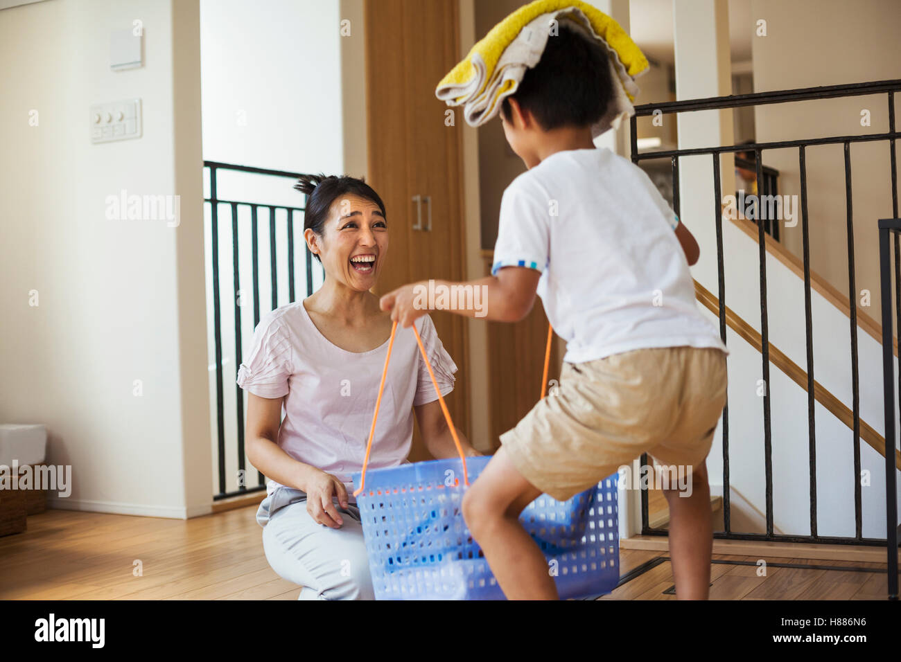 Haus der Familie. Eine Frau und ihr Sohn Sortieren der Wäsche, der junge Handtücher auf dem Kopf balancieren. Stockfoto