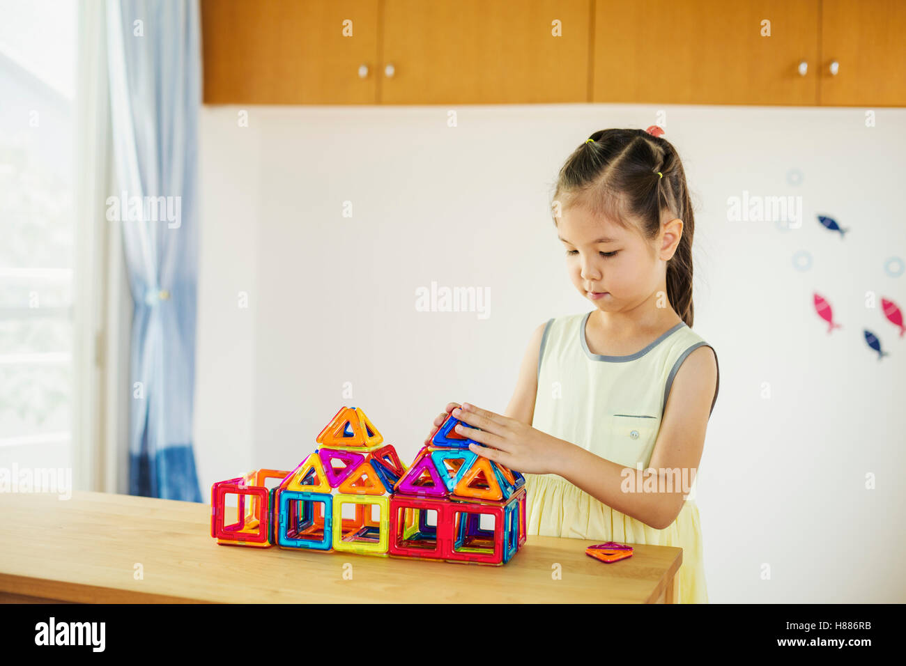 Ein Mädchen spielen, ein Gebäude mit bunten geometrischen Formen. Stockfoto