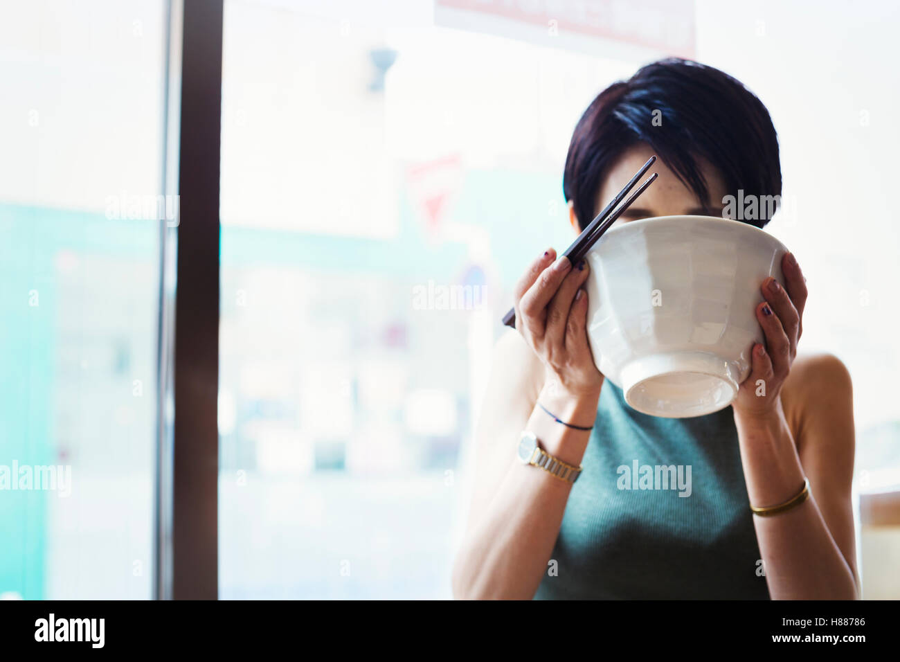 Ein Ramen-Nudel-Café in einer Stadt.  Eine Frau sitzen Essen Ramen-Nudel-Suppe, aus der Schüssel schlürfen. Stockfoto