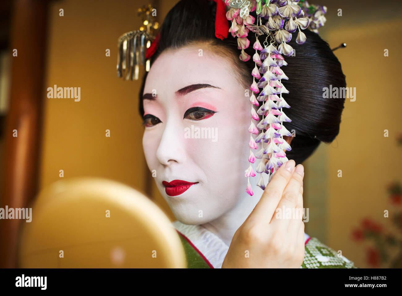 Eine Frau hat sich im Stil traditionellen Geisha, Blick in einen Handspiegel. Stockfoto