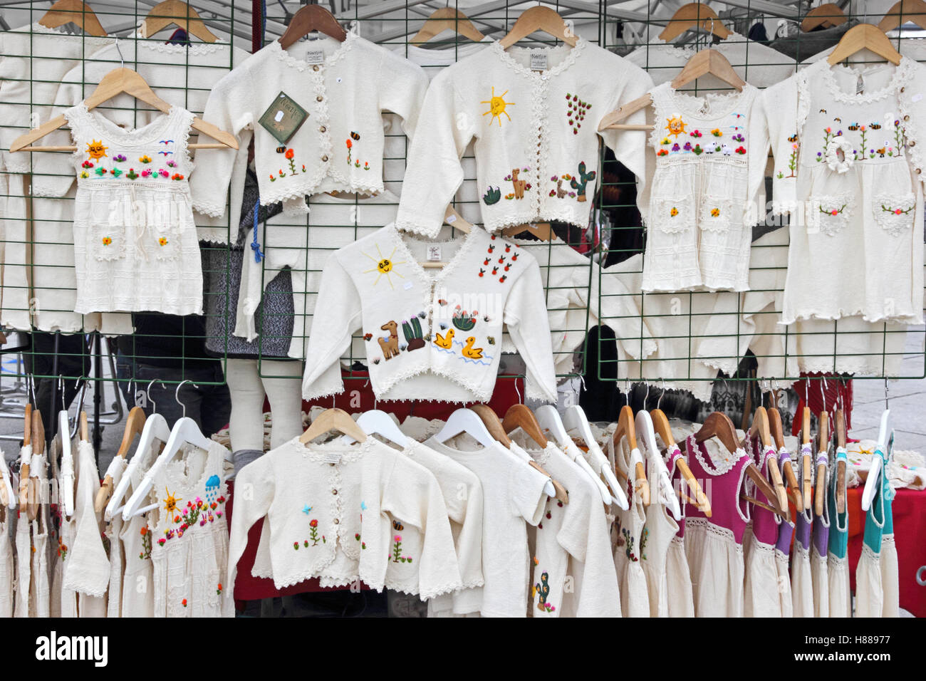 Mädchen weiße bestickte Kleider und Strickjacken für den Verkauf auf Marktstand, Stavanger, Norwegen Stockfoto