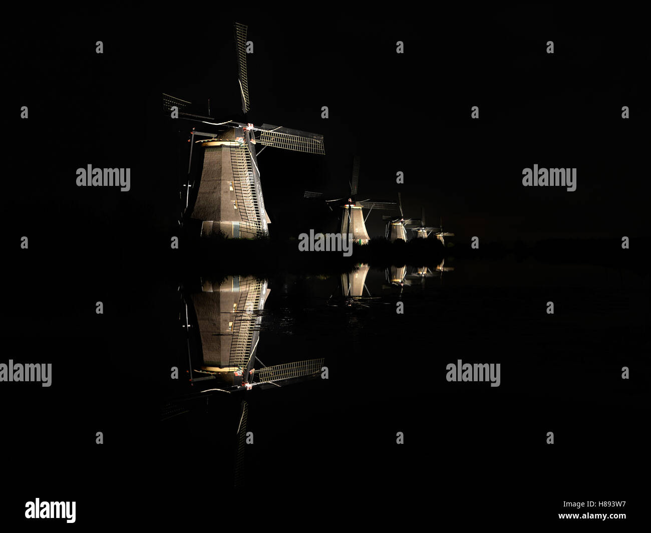 Fünf leuchtende Windmühlen, mit Spiegelbild im Wasser des Kanals in die dunkle schwarze Nacht in Kinderdijk, Niederlande. Stockfoto