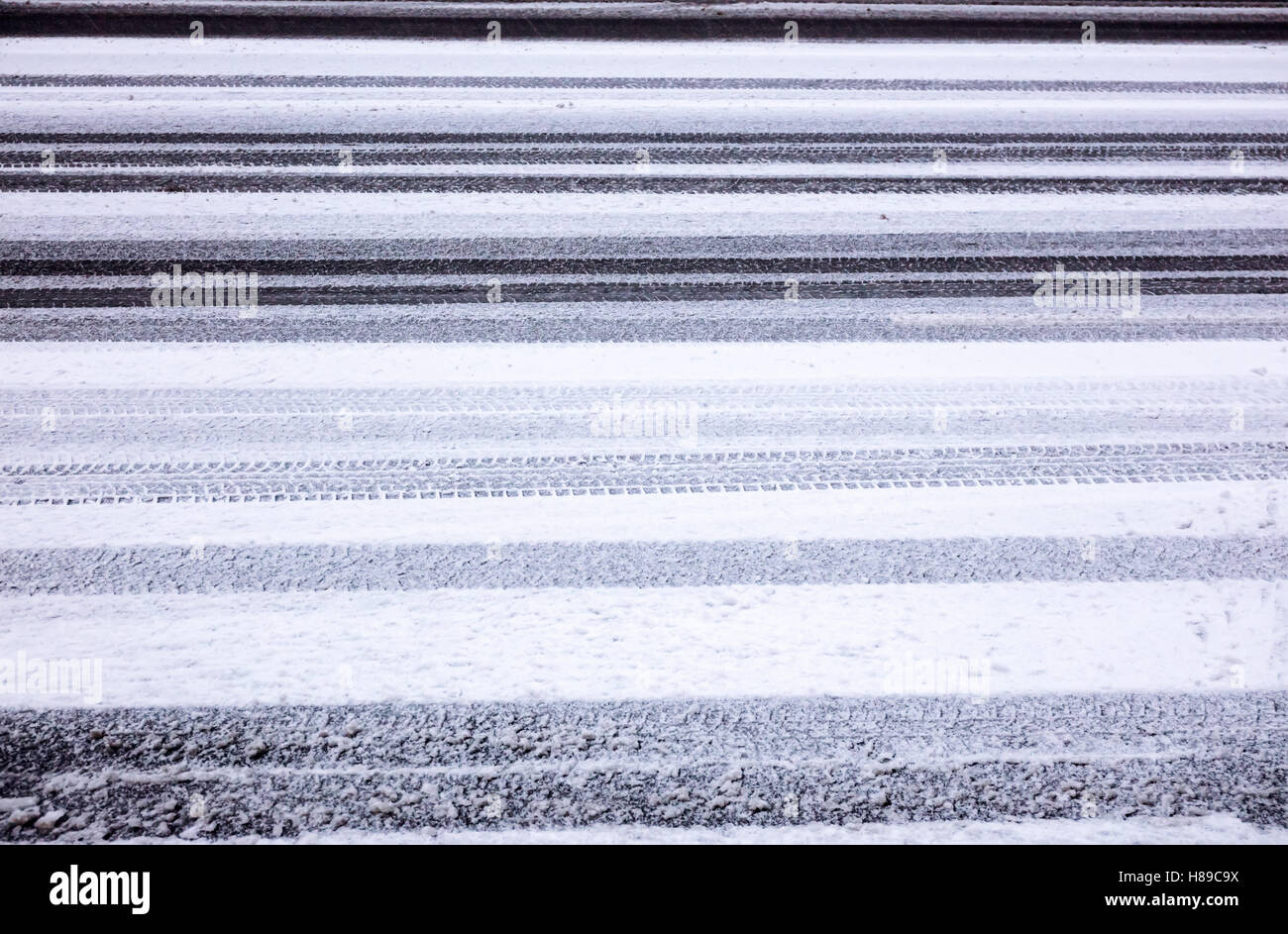 Hintergrundtextur Asphaltstraße bedeckt mit Schnee und Reifen Spuren Stockfoto