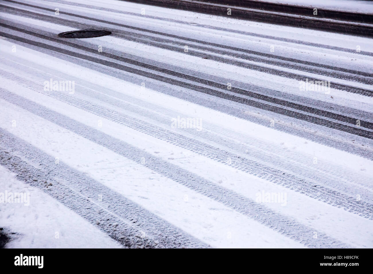 Winter-Straße bedeckt, erster Schnee und Auto Reifen Spuren Hintergrund Stockfoto