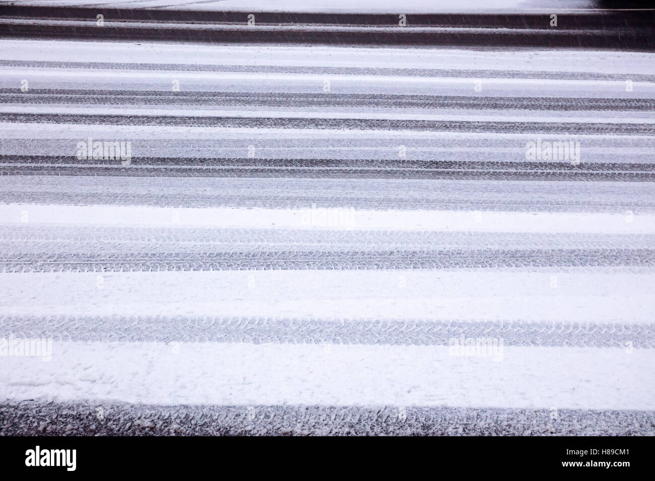 Reifen druckt in ersten Nassschnee auf Asphaltstraße Stockfoto