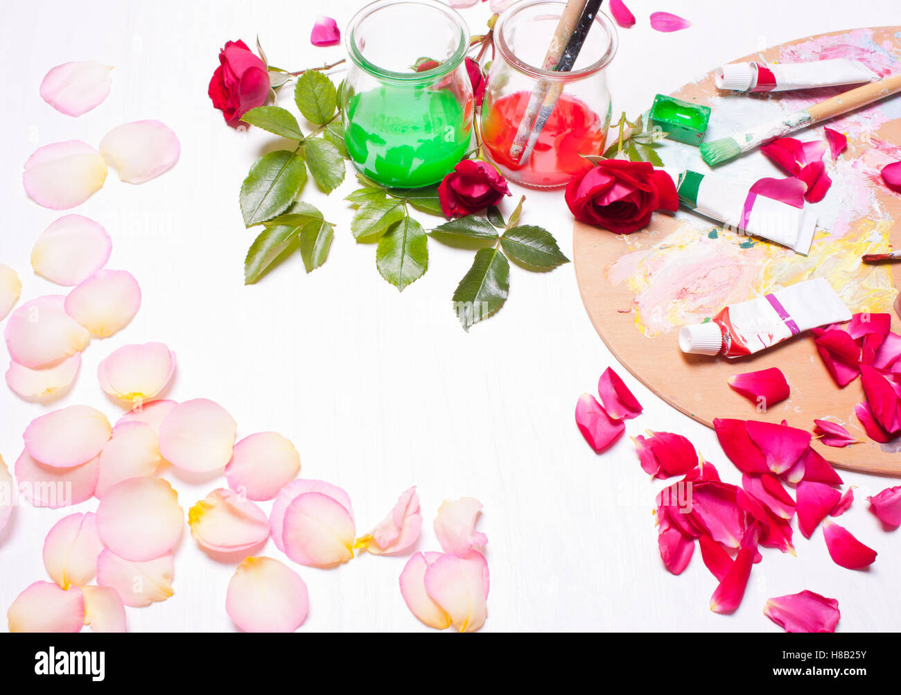 Farben und Pinsel mit Rosenblättern. Arbeitsplatz des Künstlers, Designers. Konzeptkunst, kreativ. Draufsicht Hintergrund. Stockfoto