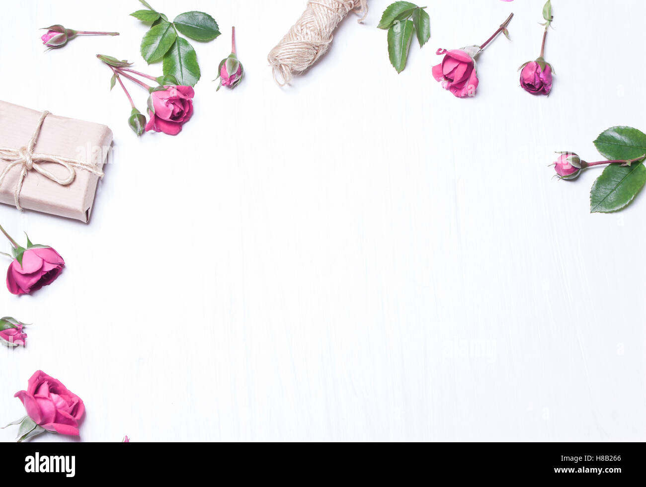 Die Zusammensetzung, Muster aus roten Rosen, ein Geschenk auf einem weißen Hintergrund. Rahmen der Blumen. Soft-Fokus. Ansicht von oben. Stockfoto